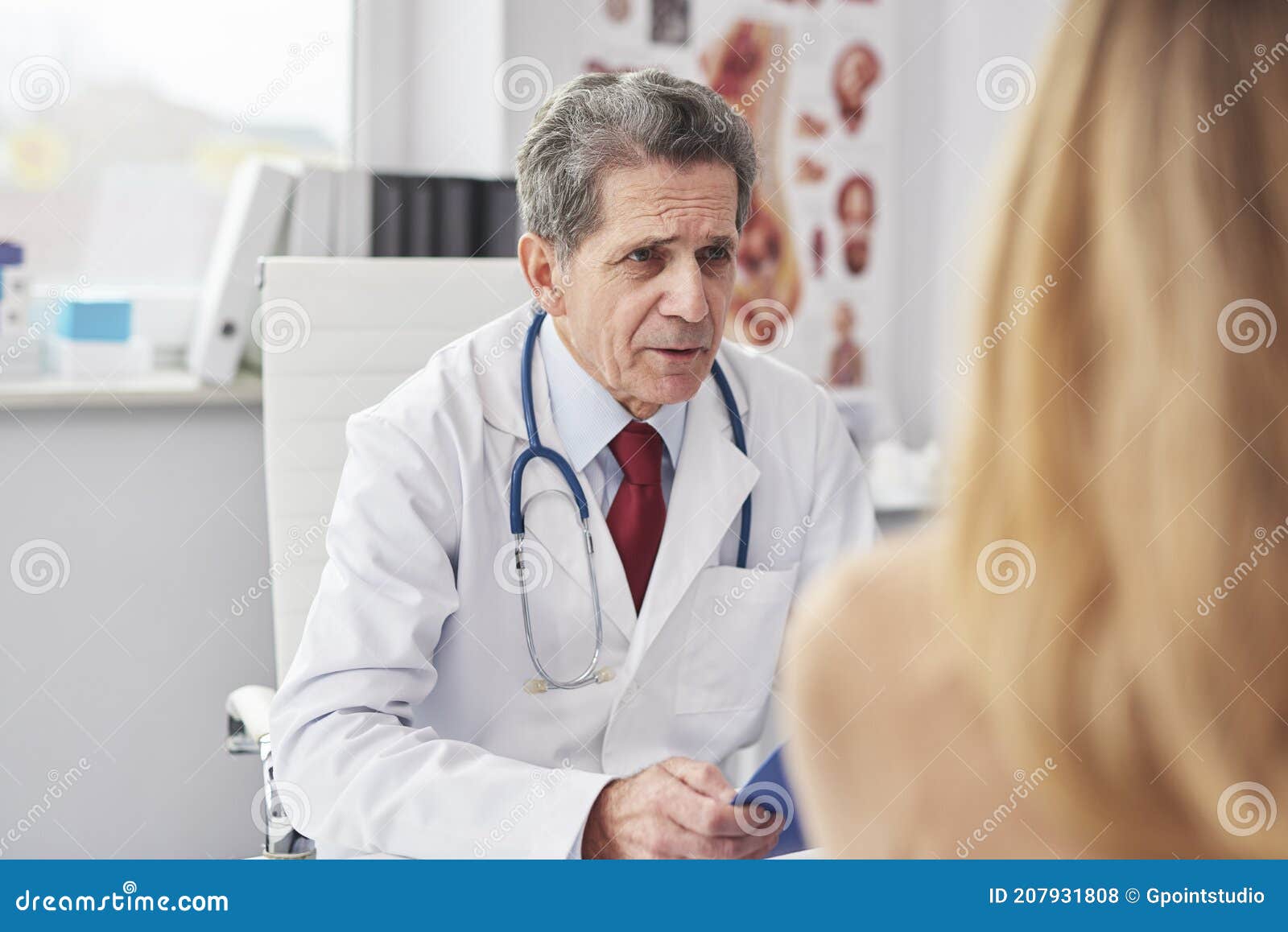 senior doctor talking with woman in doctorÃ¢â¬â¢s office